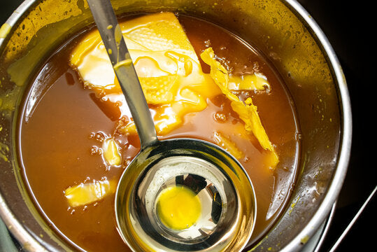 Melting raw beeswax in a double boiler with ladle, showing the natural golden color and texture—perfect for making non-toxic, homemade beeswax candles.