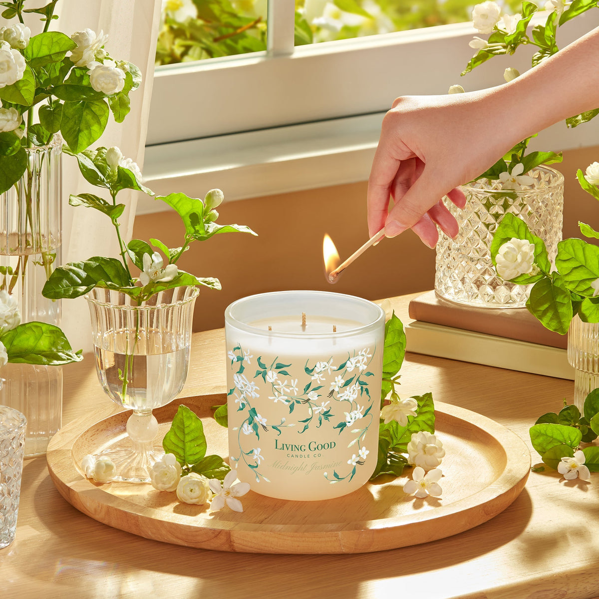 Living Good Candle Co. 15 oz three-wick beeswax candle surrounded by jasmine flowers in a bright self-care setting.