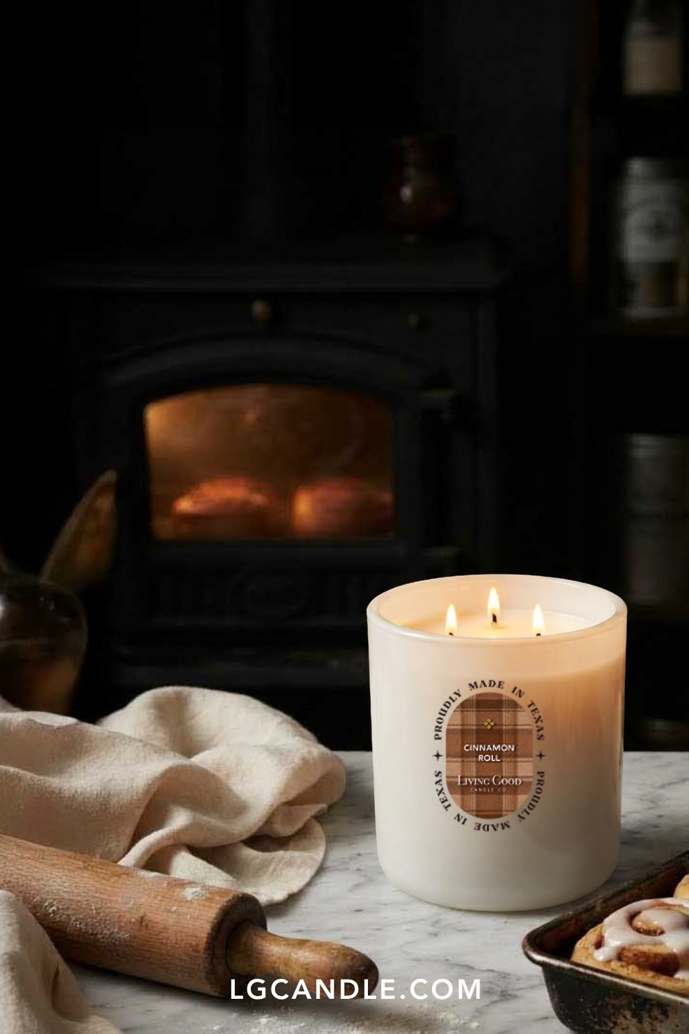 Living Good Candle Co. three-wick beeswax candle burning beside a fireplace