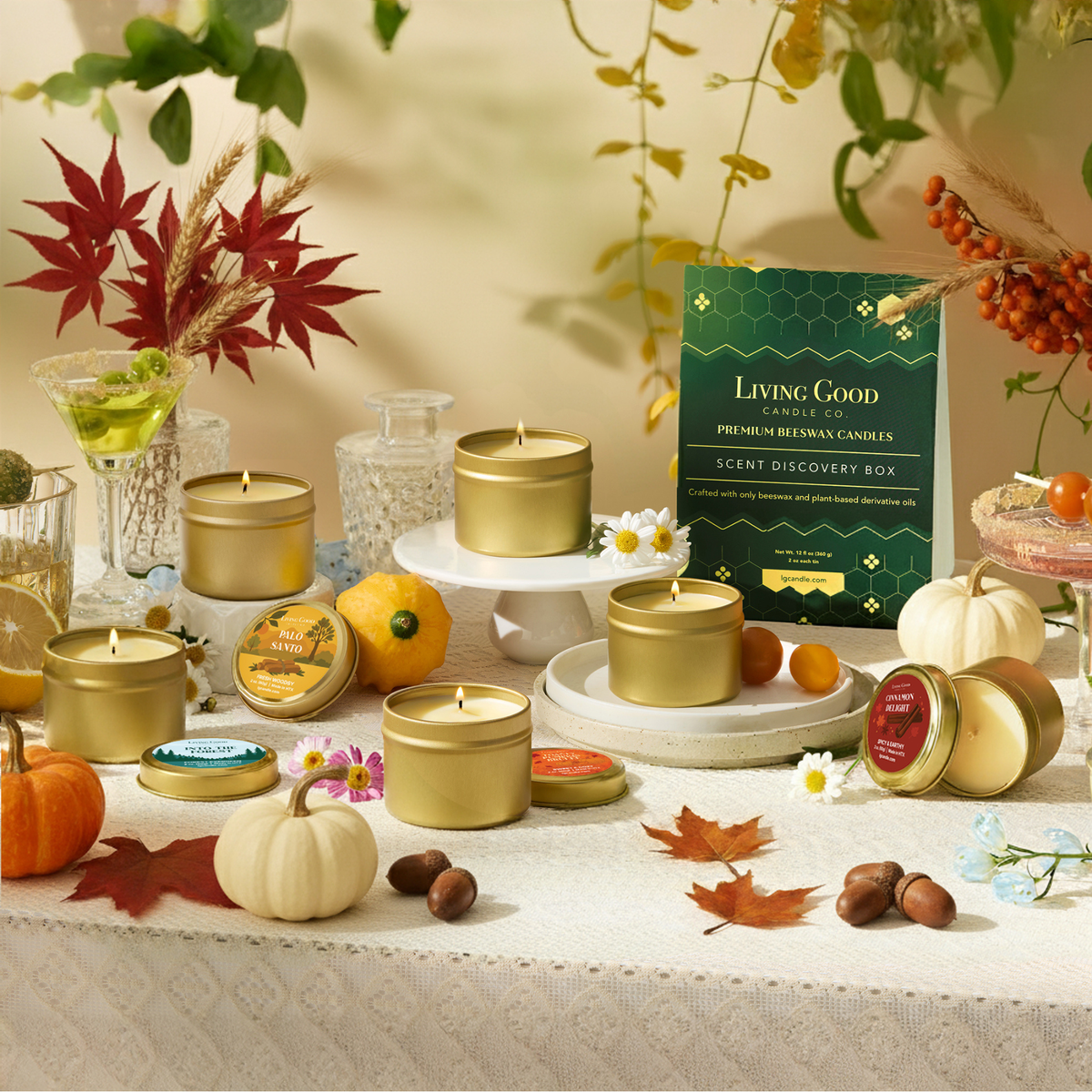 Living Good Candle Co. beeswax candle scent discovery box with gold tin candles, pumpkins, autumn leaves, and seasonal fall decor.