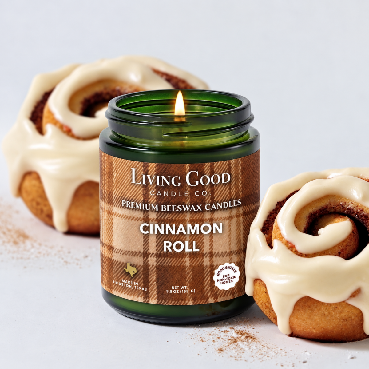 Cinnamon Roll 5.5 oz beeswax candle burning in a green glass jar beside iced cinnamon rolls.