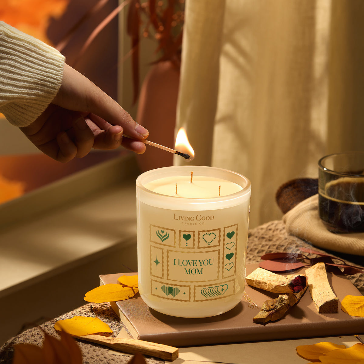 I Love You Mom beeswax candle being lit beside Palo Santo wood in a warm Mother’s Day gift setting.