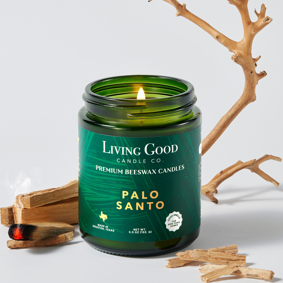 Palo Santo 5.5 oz beeswax candle in a green glass jar with palo santo wood and a lit wick