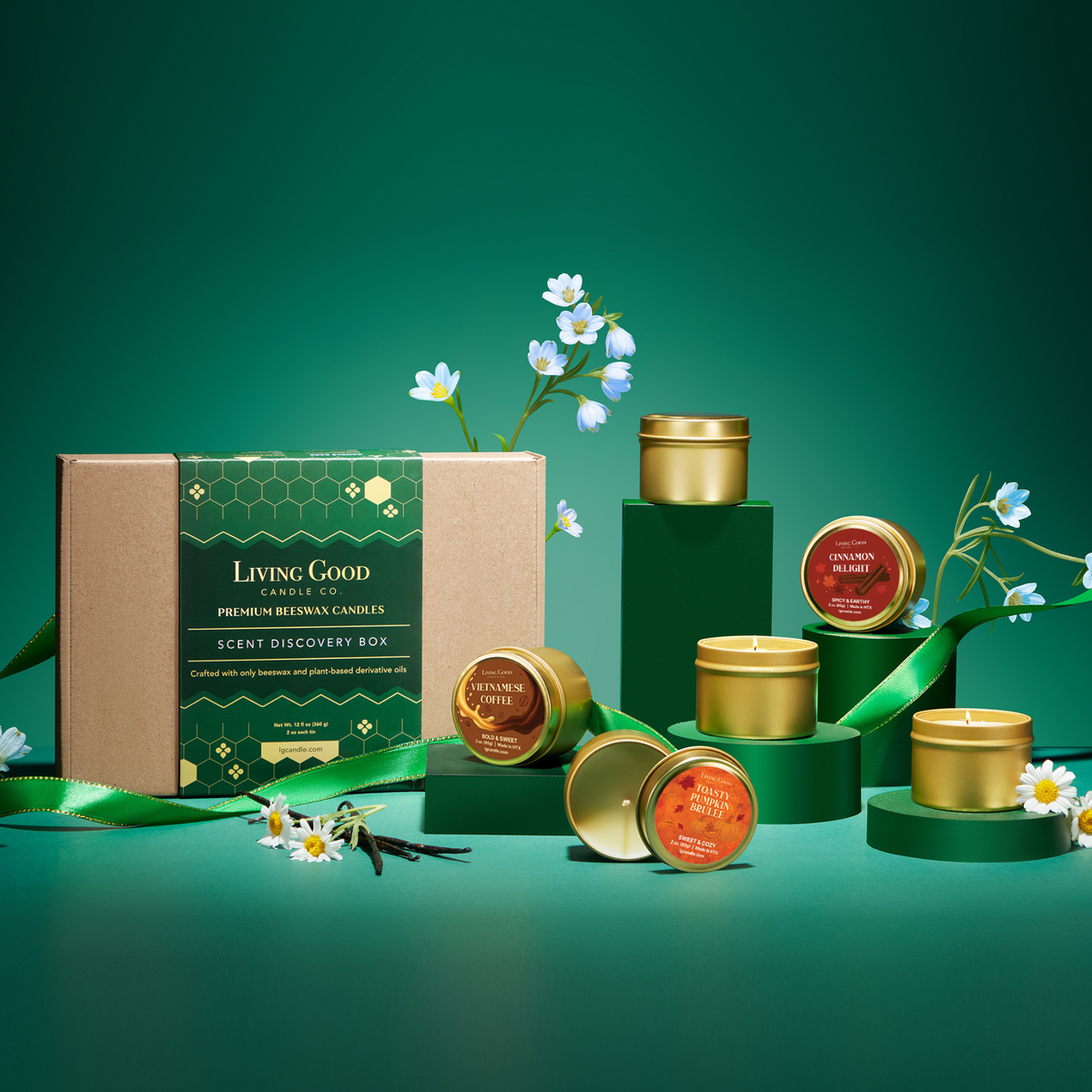 Seasonal Scent Discovery Box and mini beeswax candle gift set displayed on green pedestals with flowers and ribbon.