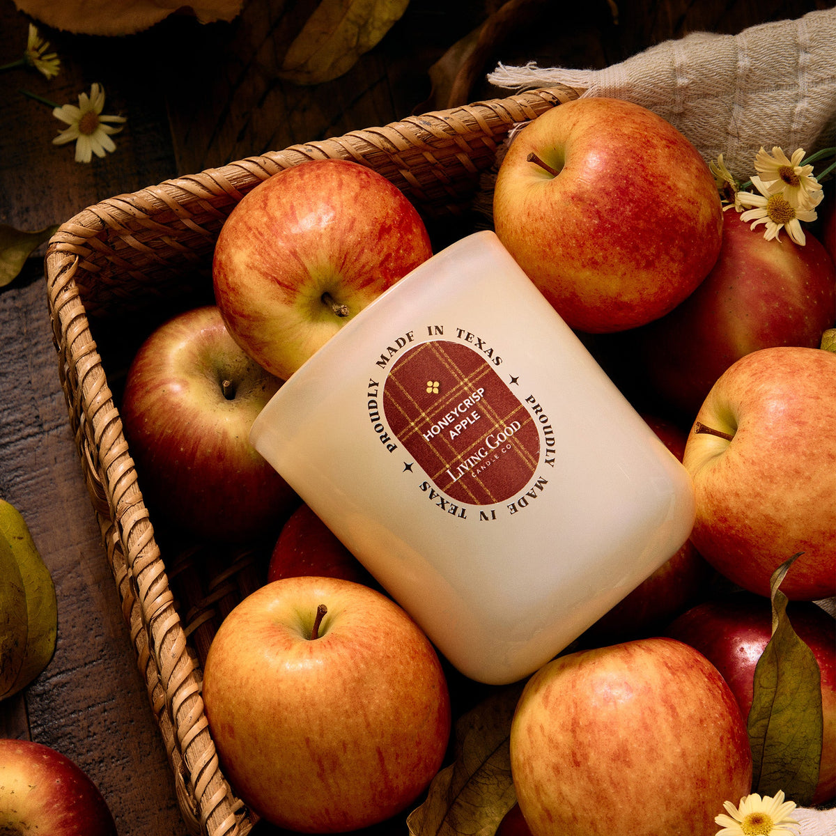 Honeycrisp Apple candle nestled in a basket of apples with daisies in golden light