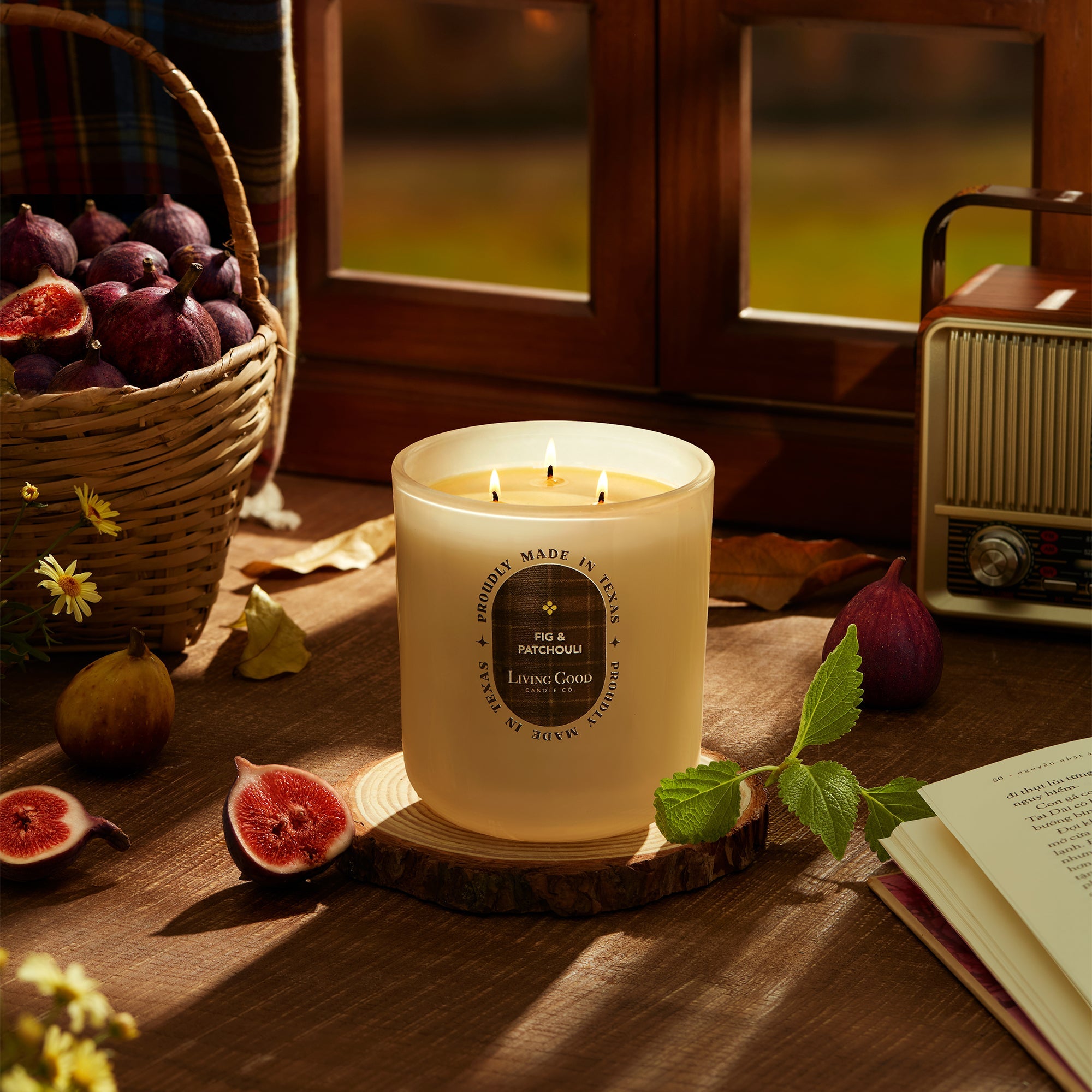 Fig and Patchouli candle in a cozy fall scene with a fig basket, vintage radio, and open book