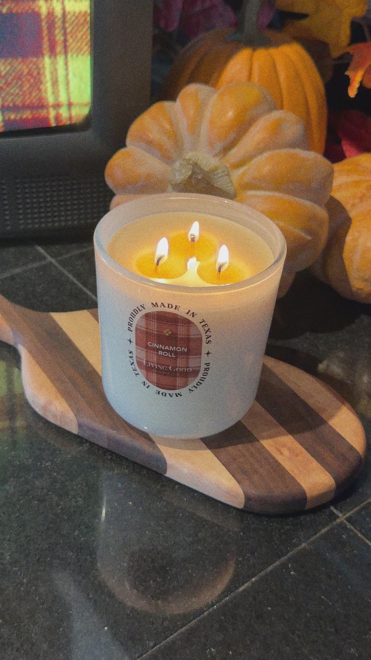 Living Good Candle Co. 15 oz Cinnamon Roll beeswax candle with three lit wicks displayed with fall pumpkins and seasonal decor.