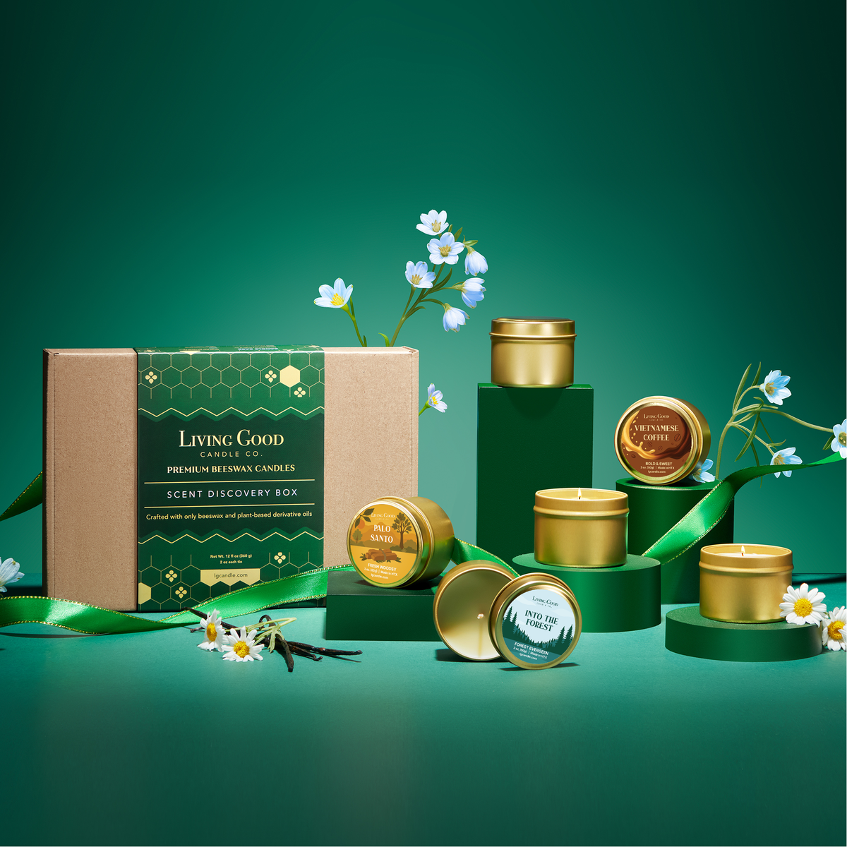 Beeswax candle discovery gift set with assorted gold candle tins displayed on green pedestals with flowers and ribbon.