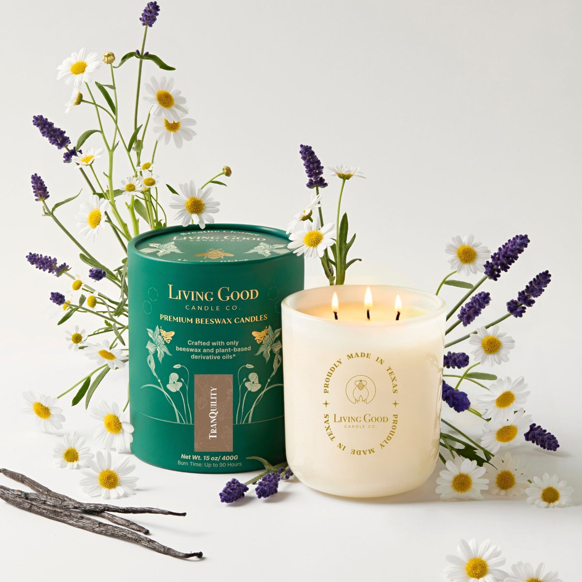 Tranquility 15 oz beeswax candle with three lit wicks surrounded by lavender and chamomile flowers